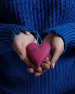 Lady in blue jumper holding a love heart cushion