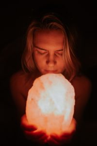 Woman holding onto a glowing salt lamp crystal