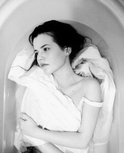Woman laying in a bath looking lost